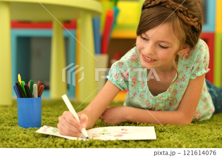 girl in the nursery draws lying on the carpet. 121614076