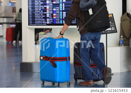 空港でスーツケースを引く旅行者 カートに荷物を積んで移動する旅行者 空港でスーツケースを引く旅行者 カートに荷物を積んで移動する旅行者 121615453