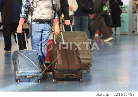 空港でスーツケースを引く旅行者 カートに荷物を積んで移動する旅行者 空港でスーツケースを引く旅行者 カートに荷物を積んで移動する旅行者 121615455
