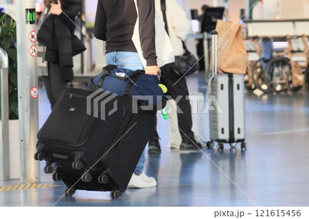 空港でスーツケースを引く旅行者　カートに荷物を積んで移動する旅行者 121615456