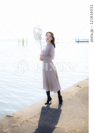 秋空の晴天のもと水辺に立つ美人ミセス。 秋空の晴天のもと水辺に立つ美人ミセス。 121616331