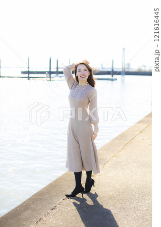 秋空の晴天のもと水辺に立つ美人ミセス。 秋空の晴天のもと水辺に立つ美人ミセス。 121616445