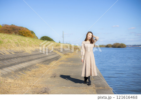 秋空の晴天のもと水辺に立つ美人ミセス。 秋空の晴天のもと水辺に立つ美人ミセス。 121616468