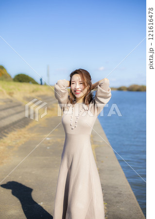 秋空の晴天のもと水辺に立つ美人ミセス。 秋空の晴天のもと水辺に立つ美人ミセス。 121616478