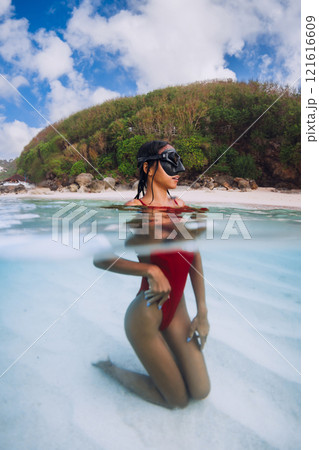 Attractive woman posing in transparent ocean. Swimming in blue water in Bali 121616609