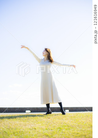 秋空の晴天のもと水辺に立つ美人ミセス。 秋空の晴天のもと水辺に立つ美人ミセス。 121616949