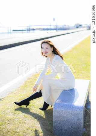 秋空の晴天のもと水辺に立つ美人ミセス。 121616966