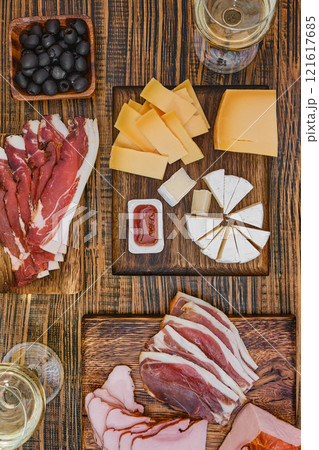 Charcuterie board with assorted meats, cheeses, olives, and sauces at a rustic wooden table Charcuterie board with assorted meats, cheeses, olives, and sauces at a rustic wooden table 121617685