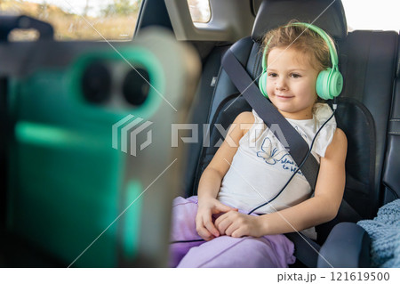Little girl with tablet and headphones in the car during travel on vacation. Entertainment in the transport for child 121619500