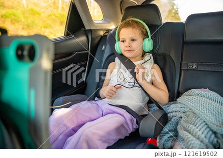 Little girl with tablet and headphones in the car during travel on vacation. Entertainment in the transport for child Little girl with tablet and headphones in the car during travel on vacation. Entertainment in the transport for child 121619502
