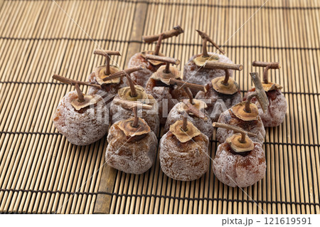 竹マット背景のへた付きの干し柿 121619591