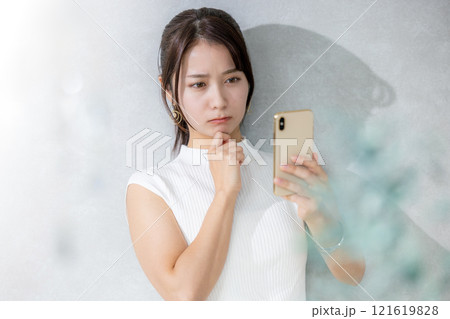 リビングでスマホを見る若い女性 121619828