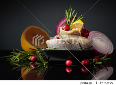 Herring fillet in oil with lemon, onion, rosemary, and cranberries. 121620659