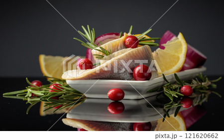 Herring fillet in oil with lemon, onion, rosemary, and cranberries. 121620662