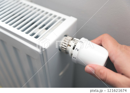 Person is adjusting the temperature on a radiator Person is adjusting the temperature on a radiator 121621674