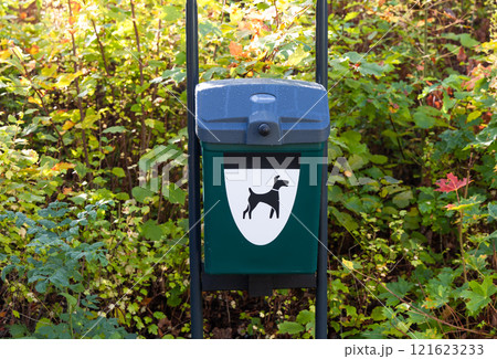 Green dog waste bin container in a park. Dog excrement cleaning, 121623233