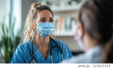 A woman in a blue scrubs is wearing a mask 121623314
