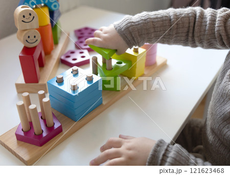 Child playing a fun-filled game of logic with colourful wooden blocks. Child playing a fun-filled game of logic with colourful wooden blocks. 121623468