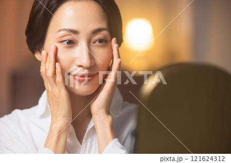 夜リビングでスキンケアをするミドル女性 121624312