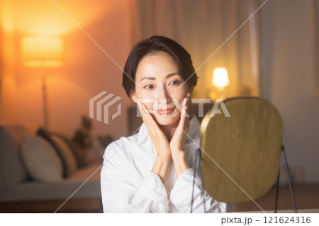 夜リビングでスキンケアをするミドル女性 121624316