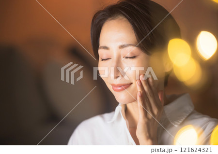 夜リビングでスキンケアをするミドル女性 121624321