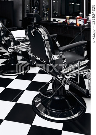 Stylish barber chairs in a modern barbershop with black and white decor 121624829