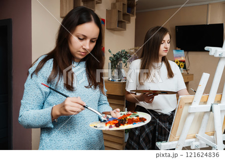 Two artists create colorful paintings in a bright studio space together 121624836