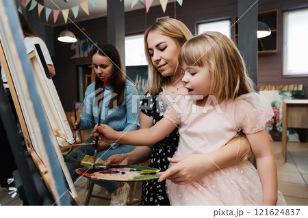 A mother and daughter create art together in a lively painting class 121624837