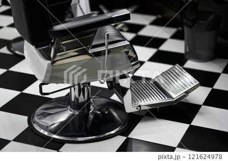 Modern barber chair with footrest in a stylish black and white salon 121624978