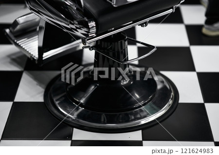 Classic barber chair on black and white checkered floor in barbershop 121624983