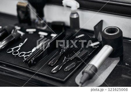 Hair salon tools neatly arranged on a black countertop at a barbershop 121625008