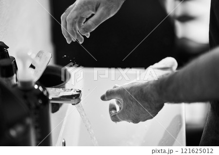 Hands washing with water at a sink in a simple setting 121625012