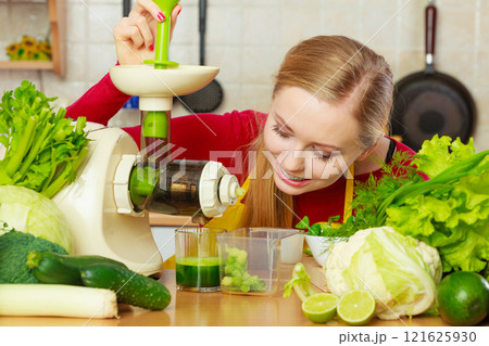 Woman in kitchen making vegetable smoothie juice Woman in kitchen making vegetable smoothie juice 121625930