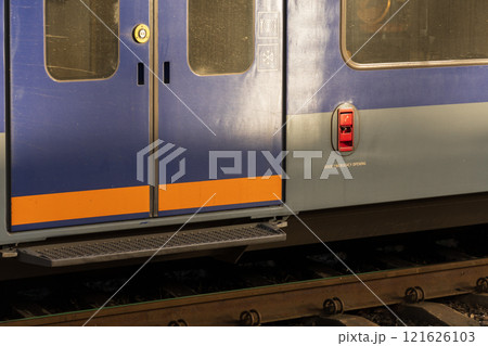 The striking blue train doors stand prominently at a busy station, highlighting their sleek design and welcoming commuters as the vibrant environment hums with anticipation 121626103