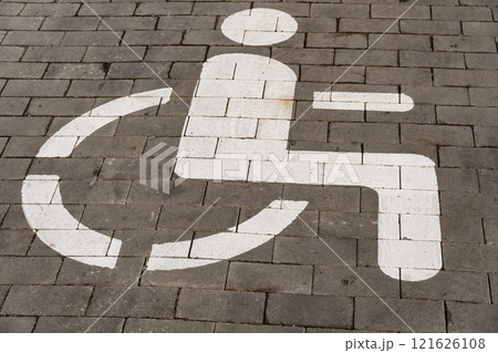 Pavement features a clear white symbol indicating a designated parking space for individuals with disabilities 121626108