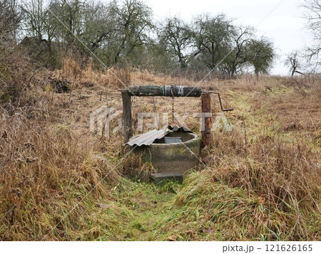 An old weathered well located in a lush, overgrown landscape, reflecting the decay of rural life and natures reclaim An old weathered well located in a lush, overgrown landscape, reflecting the decay of rural life and natures reclaim 121626165