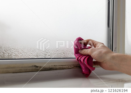 Male hand wipes the condensate from the window glass. Closeup. 121626194