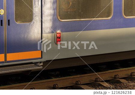 Brightly colored electric train stands at the platform, showcasing industrial design elements while passengers eagerly wait to board for their daily commute 121626238