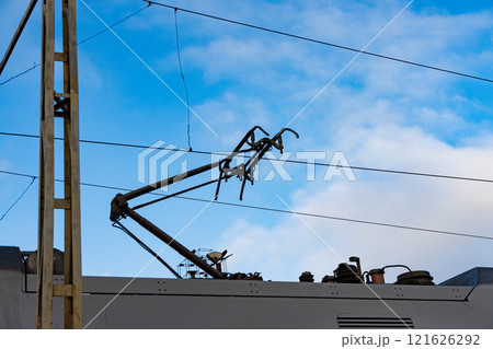 Electric train components are visible against a vibrant blue sky, showcasing the intricate design of modern railway systems and their essential infrastructure Electric train components are visible against a vibrant blue sky, showcasing the intricate design of modern railway systems and their essential infrastructure 121626292