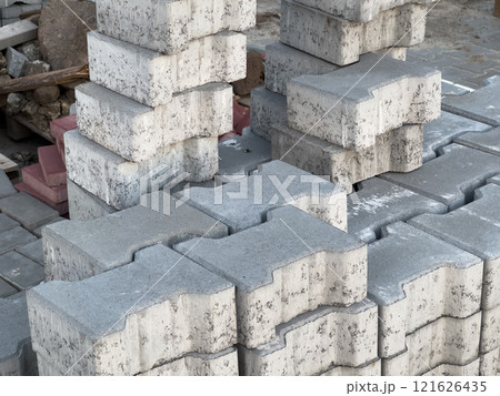 Stacked sections of grey paving stones and bricks ready for sidewalk and street construction, showcasing urban materials and an organized construction site setting 121626435