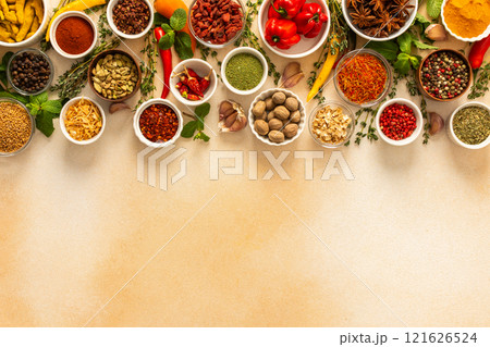 Assortment of vibrant spices and herbs on a warm beige background, showcasing a natural and aromatic palette for culinary inspiration, top view and copy space 121626524