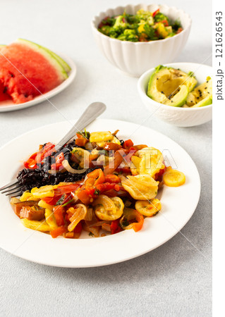A filling breakfast of black rice with stewed tomatoes, zucchini, peppers, and onions, accompanied by a fresh salad of tomatoes, broccoli, radish, and avocado A filling breakfast of black rice with stewed tomatoes, zucchini, peppers, and onions, accompanied by a fresh salad of tomatoes, broccoli, radish, and avocado 121626543