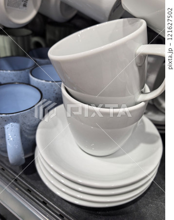 Stacked white cups and saucers in a cozy kitchen display Stacked white cups and saucers in a cozy kitchen display 121627502