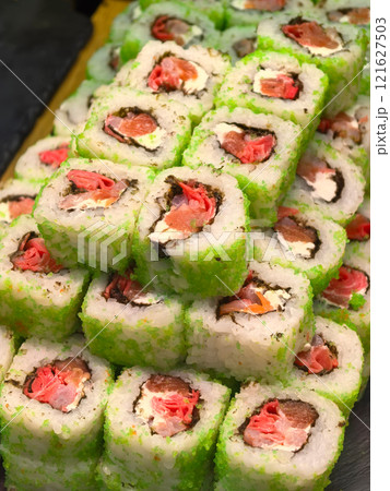 Delightful sushi rolls stacked high in a vibrant green display Delightful sushi rolls stacked high in a vibrant green display 121627503