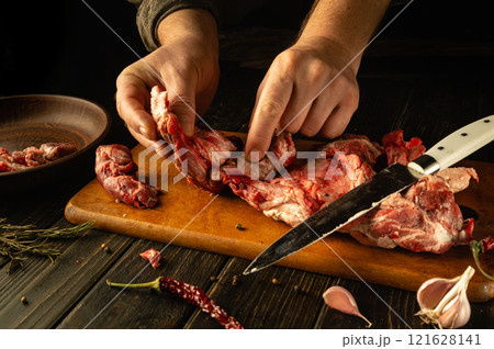 Hands expertly dissect various cuts of meat on a wooden board, showcasing a blend of skillful technique and culinary passion. The rustic atmosphere amplifies the artistry of butchery Hands expertly dissect various cuts of meat on a wooden board, showcasing a blend of skillful technique and culinary passion. The rustic atmosphere amplifies the artistry of butchery 121628141
