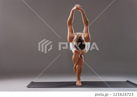 woman doing yoga sitting in Gomukhasana exercise cow face pose working out wearing white sportswear indoor full length studio background, woman doing yoga sitting in Gomukhasana exercise cow face pose working out wearing white sportswear indoor full length studio background, 121628723