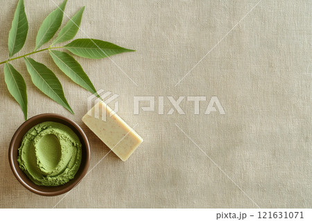 Flat lay view of neem leaves and herbal products on a textured surface 121631071