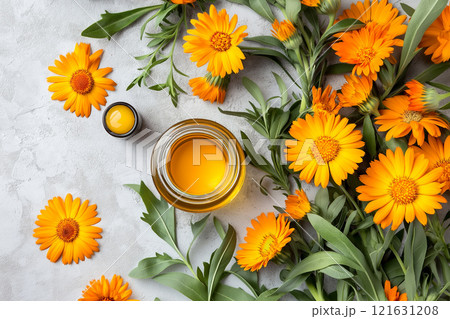 Bright calendula flowers and oil displayed on a light stone surface 121631208