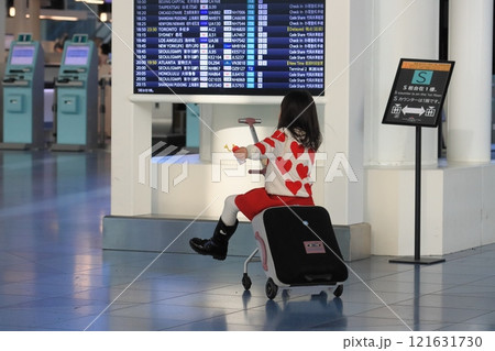 キャリーバッグにまたがって空港ロビーを移動する訪日客 キャリーバッグにまたがって空港ロビーを移動する訪日客 121631730