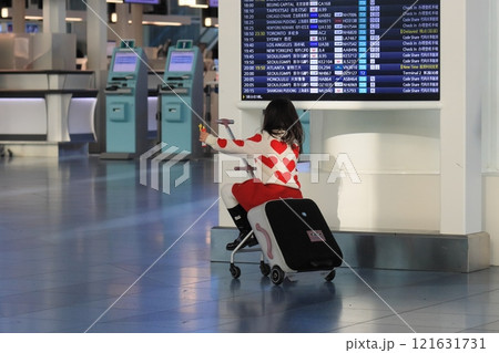キャリーバッグにまたがって空港ロビーを移動する訪日客 121631731